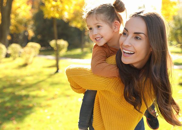 young woman with toddler on her back in a park
