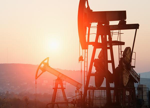 oil derricks in front of a sunset