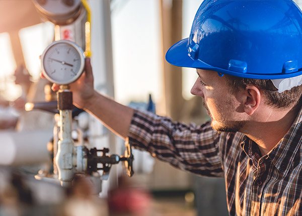 man in hard hat reading a gauge