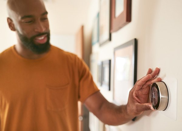 man adjusting thermostat on wall