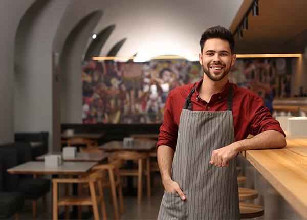 man in an apron standing at a restaurant bar